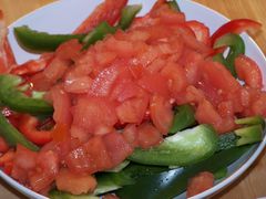 In Streifen geschnittene rote und grüne Paprika sowie gewürfelte Tomaten für den Tofu-Gulasch