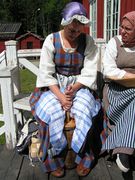 Eine schwedische Frau ist mit einem Stoßbutterfass beim Buttern.