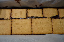 Die Kekse und die Schokomasse abwechselnd in eine mit Backpapier ausgelegte Form schichten…