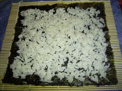 Den Reis auf dem Nori-Blatt verteilen, oben und unten etwas Platz lassen.