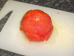 Die Haut der Tomate abziehen und den Stielansatz entfernen