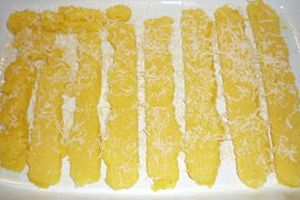 Die in Scheiben geschnittene Polenta wird in die Auflaufform geschichtet und mit Parmesan bestreut.
