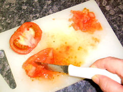 Die Tomaten halbieren, Kerne mit dem Gemüsewasser entfernen und das Tomatenfleisch hacken