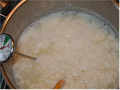 Die gerinnende Milch nach Zugabe der Säure. Man erkennt das leichte Grün der Molke.