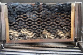 Holzkohlegrill mit seitlichem, gefüllten Kohlefach vor dem Anzünden